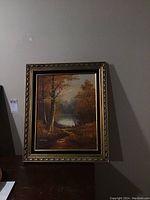 Framed painting showing a full view of the artwork and frame against a wall.