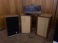 Garrard record player on top of a wooden surface with transparent cover and three bookshelf speakers arranged around it.