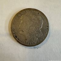 Front side of the 1890-O Morgan silver dollar coin showing worn Lady Liberty profile, date 1890 visible at the bottom.