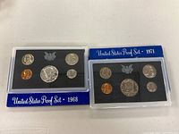 Two US Mint Proof Sets from 1968 and 1971 in their original display cases with five coins each.