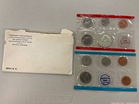 Photo of the original envelope from the Treasury Department along with two complete 1970 US proof coin sets sealed in original plastic holders with coins arranged by denomination.