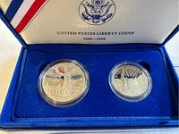 Close-up of two 1986 Liberty coins inside a blue velvet presentation case with United States emblem and text 'United States Liberty Coins 1886-1986'. The coins are individually encased in clear plastic capsules.