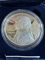 Close-up of the 2005 Chief Justice John Marshall proof silver dollar coin in protective casing showing detailed portrait and inscriptions.