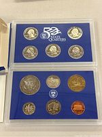 Photo of the 2005 US Mint Proof Set coins inside the blue plastic case, showing 5 state quarters (Delaware, Pennsylvania, New Jersey, Georgia, Connecticut) on the top half and 4 coins (half dollar, dime, nickel, penny) on the bottom half.