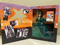 Open box showing Barbie doll in green dress with gold trim and matching headpiece, along with film stills from Gone with the Wind inside the box.