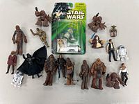 Top-down photo showing the entire lot: multiple Star Wars action figures including several Chewbacca figures, the R3-T7 figure still in blister pack, and other character figures including Darth Vader, Luke Skywalker, Han Solo and others.