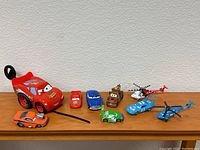 All eight toy vehicles on display, including Lightning McQueen ride-on and various smaller character cars and helicopters.