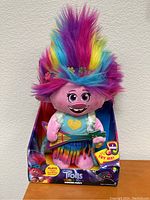 Front view of the Trolls World Tour Dancing Poppy plush doll in original packaging showing colorful rainbow hair, holding guitar, with Try Me sticker and branding details.