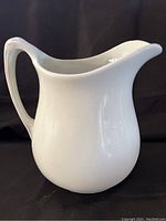 Full side view of white Alfred Meakin ceramic pitcher with smooth curved body, wide pouring spout, and sculpted handle.