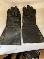 Top view of black genuine leather Bristol Heritage summer riding gloves laid flat with cuffs extended, showing stitching and logo patch.