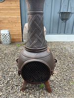 Front view of the cast iron chiminea showing the main body, door with mesh, latch, and copper trim.