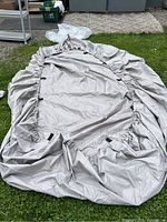 Large canvas cover laid out on the ground showing fabric and gathered elastic edges.