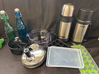 Photo showing two Thermos insulated coffee flasks, two colorful glass salad dressing bottles, silicone ice cube trays with covers, and the stainless steel topped manual food chopper/spinner.