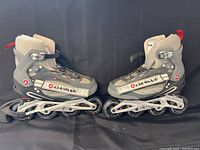 Photo showing pair of black, gray, and red Airwalk inline rollerblades side by side on a black background.