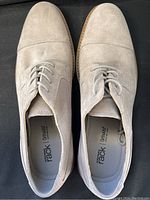 Top-down view of both beige suede dress shoes showing cap-toe design and lacing.
