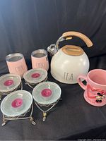 Full lot including white Rae Dunn teapot, two pink stainless steel wine glasses, four pewter tealight holders with pink candles, and pink Minnie Mouse mug.