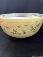 Side view of three nested Pyrex mixing bowls showing green Shenandoah floral pattern on cream colored exterior.