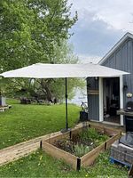 Full view of the umbrella open over outdoor garden bed and deck area with lake in background