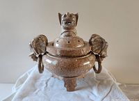 Front view showing the foo dog lid figure and elephant head handles