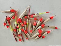 Photo showing approximately 30 new wooden fishing bobbers with bright orange tops and natural wooden bodies.