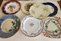 Top view of seven decorative collectible plates showing different floral and geometric designs.