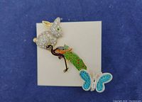 Photo of three vintage animal-themed brooches on blue background: rabbit, peacock, butterfly
