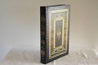 Front cover showing black leather with gold embossed design including a rectangular frame and central motifs.