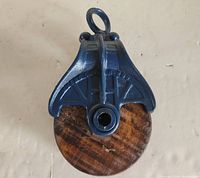 Front view of the barn pulley showing the wooden wheel and cast iron frame with eyelet.