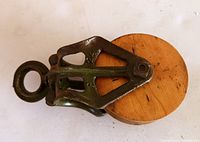Top-side view of refurbished barn pulley showing metal frame and wooden wheel