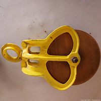 Top view of the yellow painted metal barn pulley showing the heart-shaped frame and central bolt.