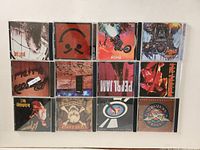 12 rock music CDs laid flat showing album covers in jewel cases