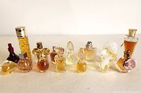 Front view of 13 assorted vintage mini perfume bottles showing shapes, colors, and stoppers