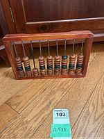 Wooden abacus positioned upright on wooden floor showing full frame and beads.
