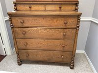 Full front view of oak chest-on-chest dresser showing all drawers and turned posts