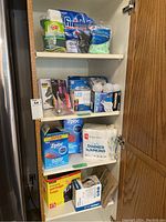 Overall photo of cabinet shelves showing all household items including light bulbs, napkins, ziplocks, and garbage bags.