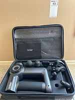 Complete Urikar massager set in fitted black carrying case with device, six massage heads, and charger cable