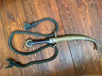 Photo showing the full dagger sheathed with green braided carrying cord laid alongside it.