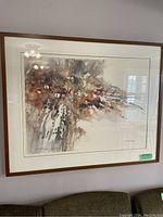 Framed watercolor style print in earthy colors depicting an abstract scene with animals, wall-mounted inside a wooden frame with glass.