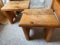 Pair of early pine wooden square stools placed on carpet showing the top surfaces with visible knots and surface wear.