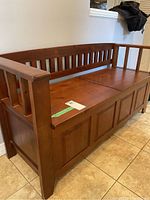 Side and front view of the brown pine wood hall bench showing slatted backrest and armrests, and the seat divided into two lids.