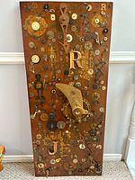 Overall photo of the wood board collage showing various clock and watch parts with prominent letters and mechanical elements arranged on the surface.