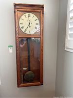 Front view of oak case wall clock mounted on wall