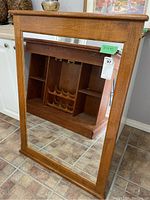 Front view of the rectangular wall mirror with natural wood frame showing minor surface wear and reflections.