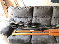 Connelly EP Limited black slalom water ski with bindings and the two wooden paddles laid on a gray couch.