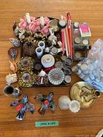 Top-down photo of entire lot showing assorted candleholders, candles, tea lights in packaging, decorative shells, artificial pink roses, and a wooden tray.