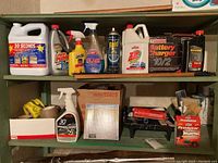 Shelves with various cleaning products, battery charger, pest control sprays and paint supplies