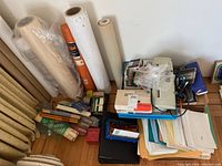 Wide view showing large rolls of paper or drafting film, shredder, various office supplies stacked on floor