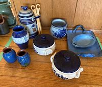 Photo showing collection of two ceramic lidded pots with blue floral designs, several pottery vases in blue hues, stein with lid, metal tray, and ceramic soap dish
