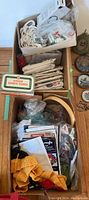 Overview of the sewing supplies showing the Singer automatic zigzag attachment box, paper patterns, yarn, and other sewing material in boxes