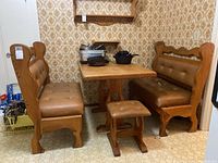 Full view of wooden table with two benches and wooden stool around it, upholstery brown with some seat damage